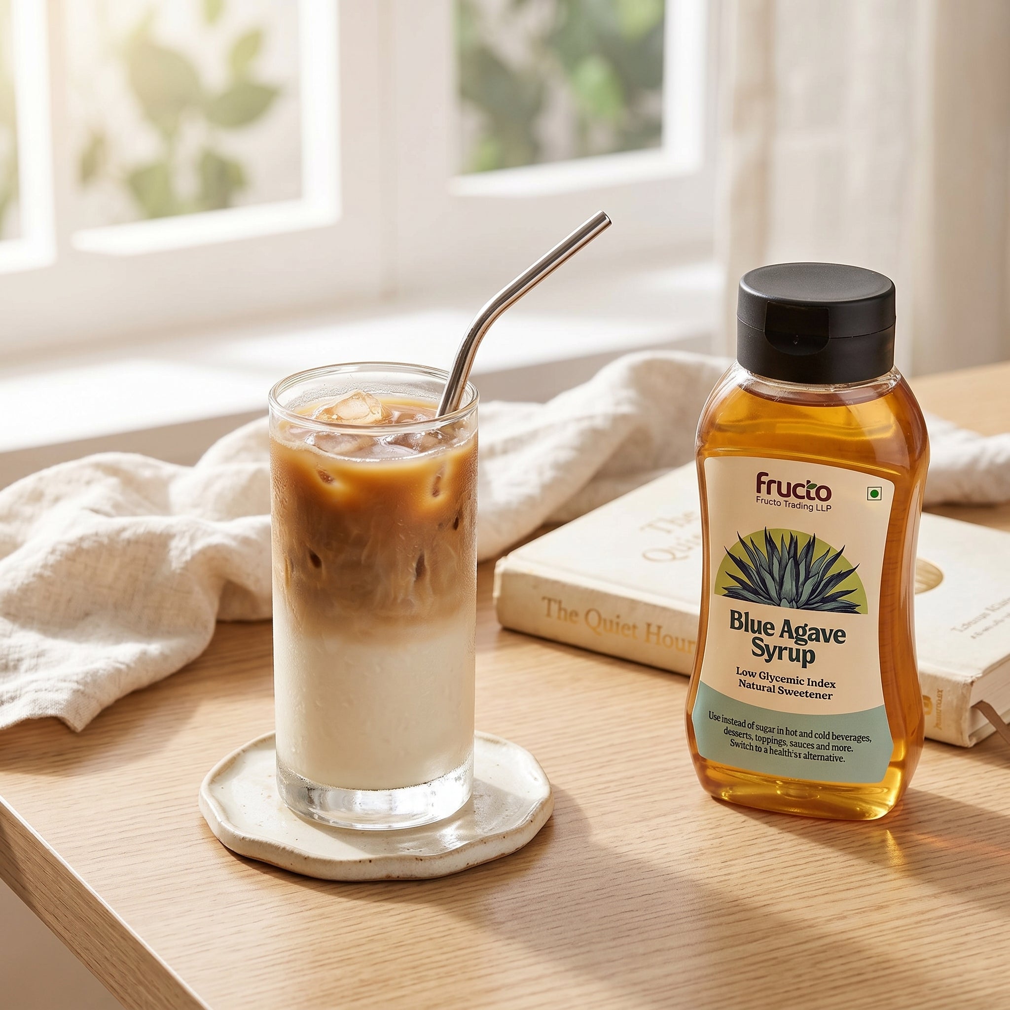 Fructo Blue Agave Syrup by window with iced coffee and book